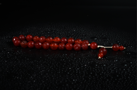 Antique-red agate tasbih on dark textured backdrop