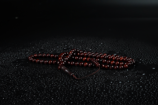 Cocoa wood color wooden Tasbih on a black textured surface