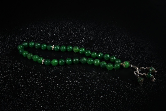 Agate green beaded Tasbih with silver tassel on black background with water droplets