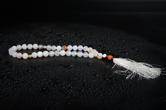 Cream agate tasbih on dark textured backdrop
