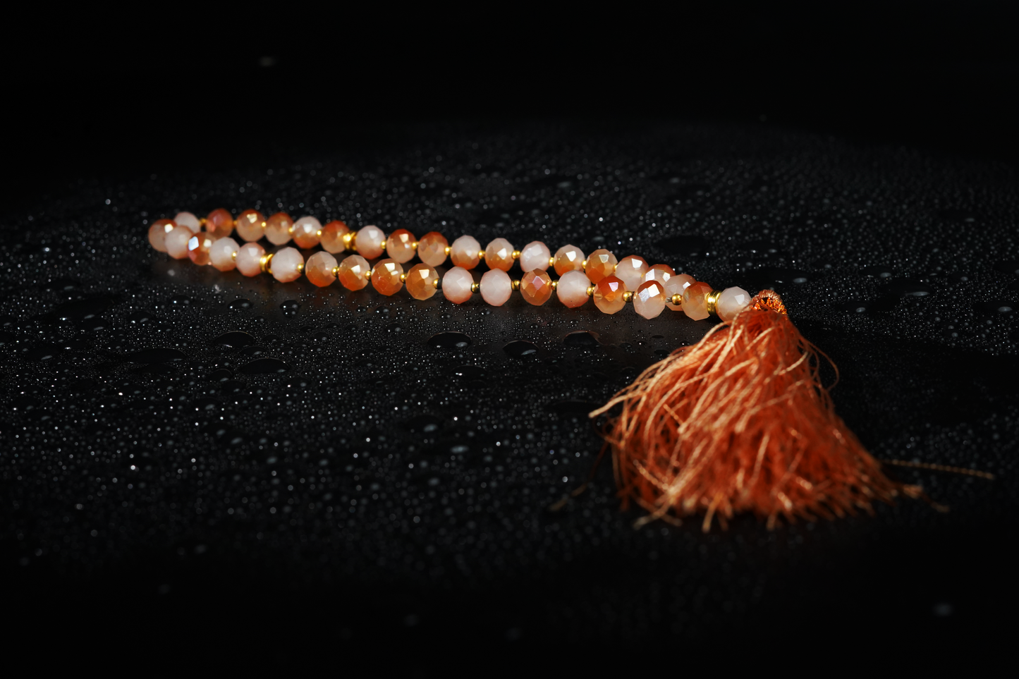 Amber resin tasbih on dark textured backdrop and droplets