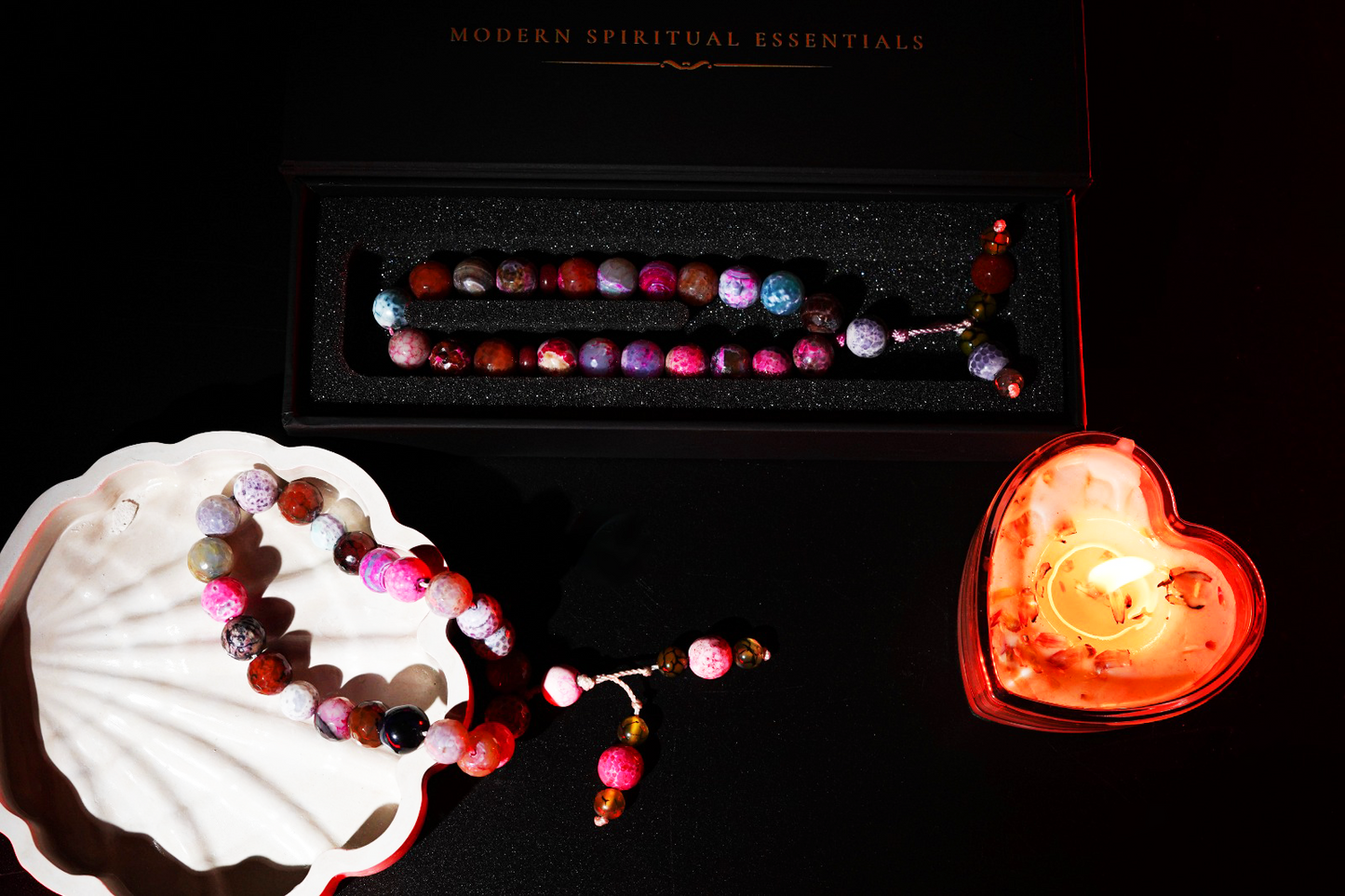 Aurora agate tasbih draped on river stones with warm light