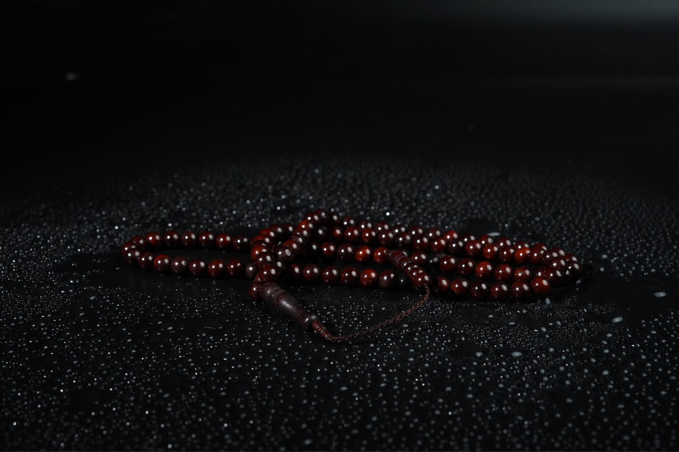 Cocoa wood color wooden Tasbih on a black textured surface