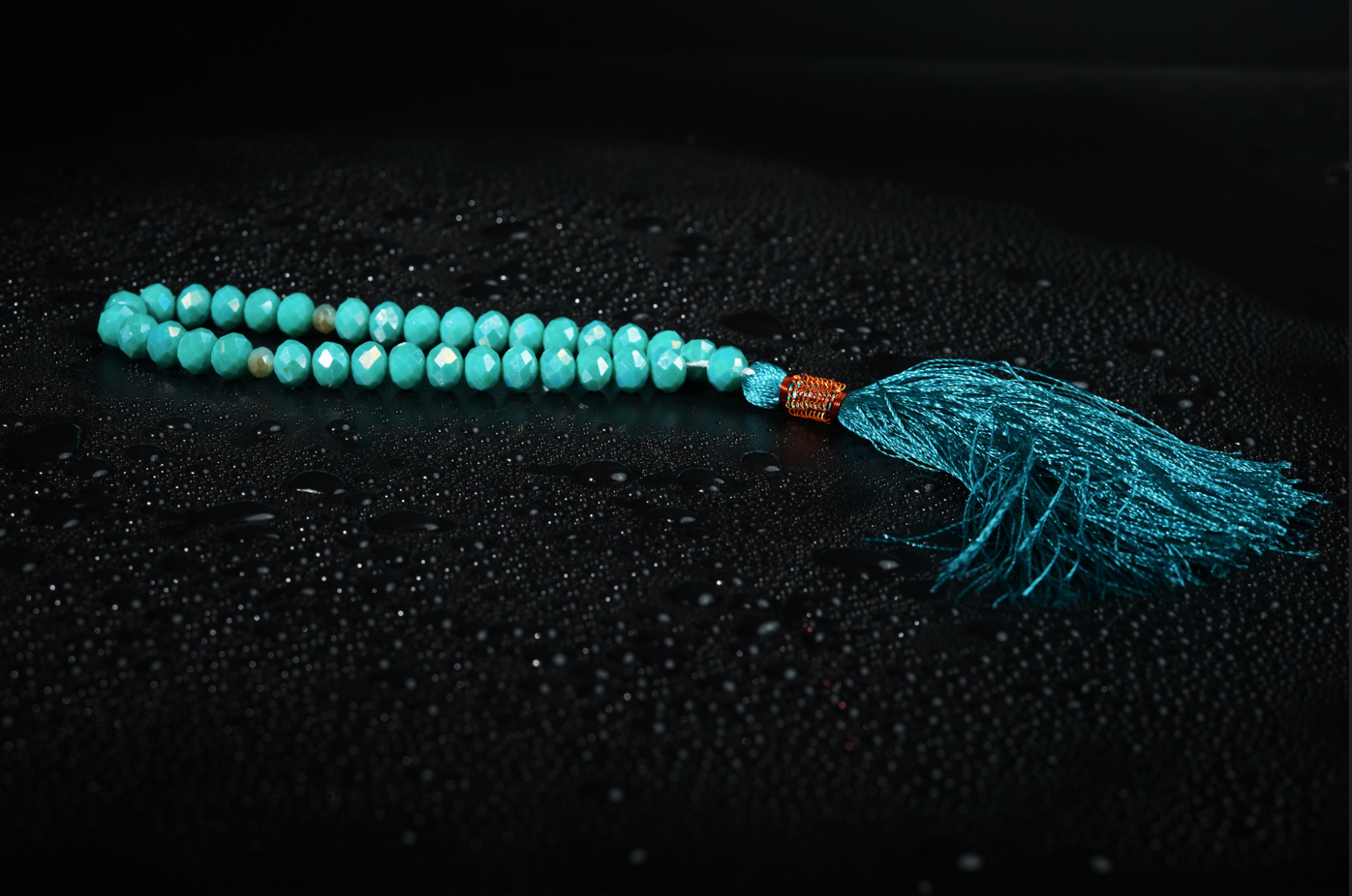 Seafoam resin tasbih on dark textured backdrop with droplets
