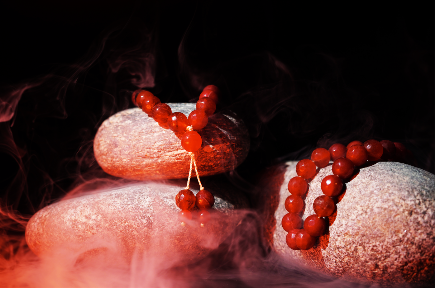Red agate prayer beads styled on stones with mist